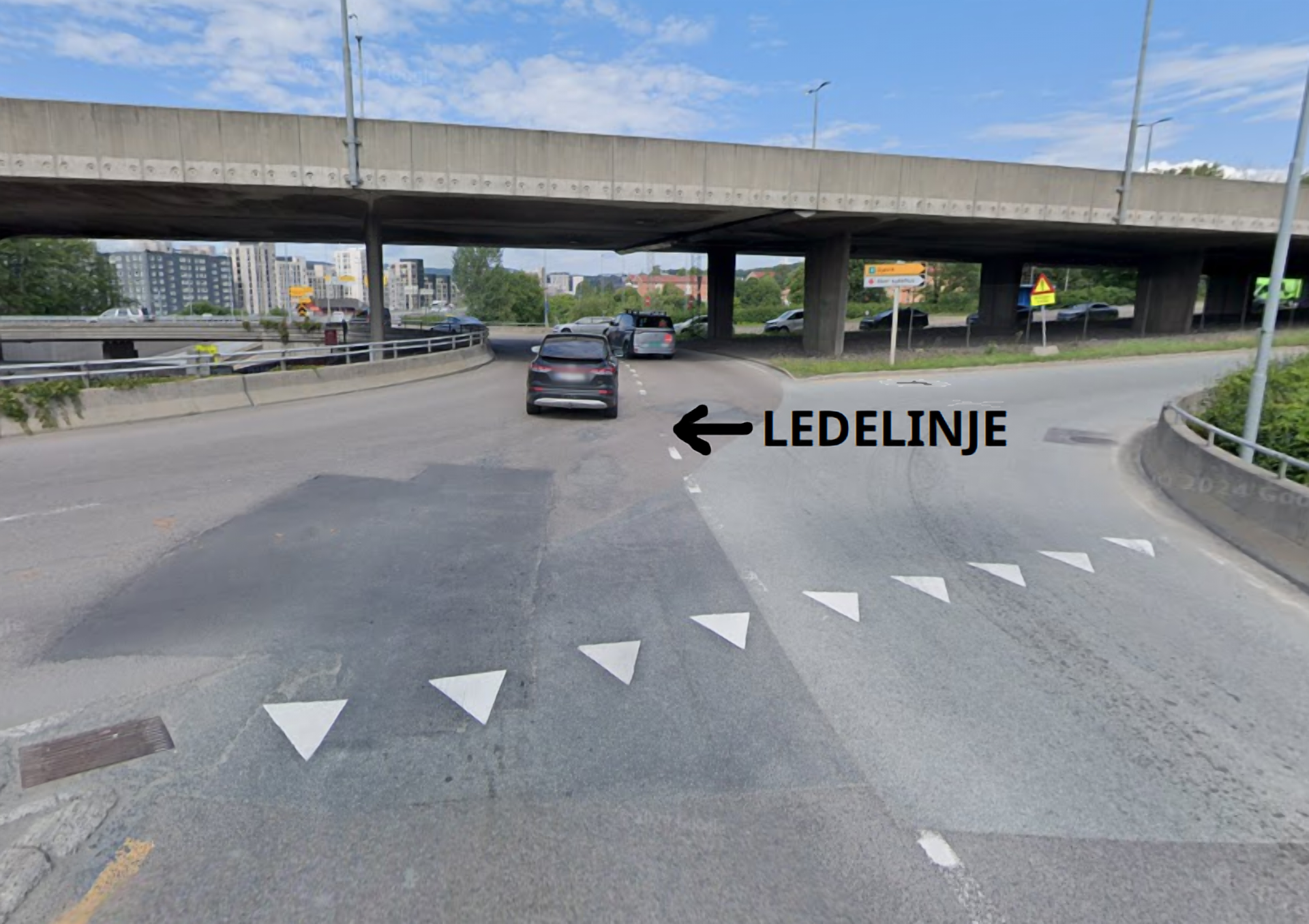 Image of a roundabout with two lanes in and out. A white guide line is clearly marked through the roundabout to show drivers how to keep their cars in the correct lane.