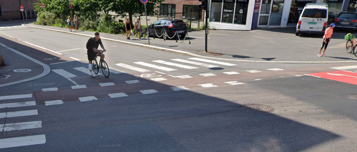 Et bilde av en sykkelkryssing i et veikryss med fotgjengerfelt ved siden av
