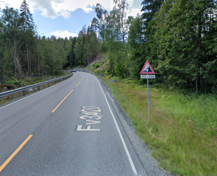 Bilde av fare for ras høyre-skiltet ved en fjellvegg